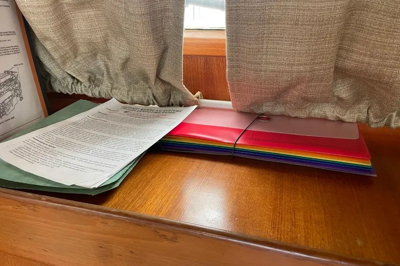 Slide: The Image of Documents and colorful folders on a wooden surface inside a 1991 Marine Trader 34 Double Cabin. - 39