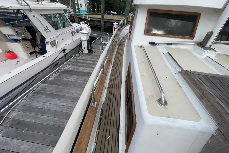 Slide: The Image of 1991 Marine Trader 34 Double Cabin docked beside another boat, showing deck and railing. - 53