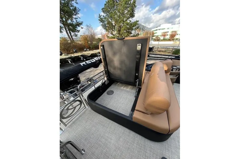 Slide: The Image of 2025 Regency 230 LE3 Sport boat with open storage compartment and tan seating. - 15
