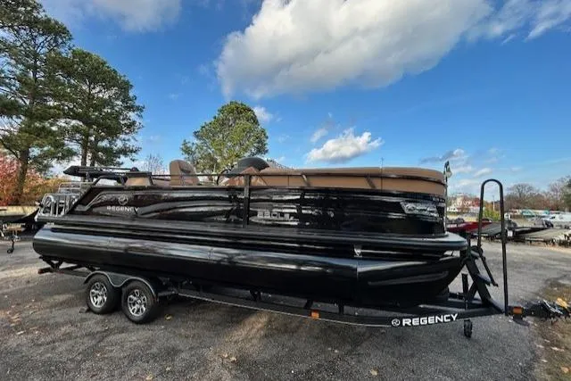 Slide: The Image of 2025 Regency 230 LE3 Sport pontoon boat on trailer, parked outdoors under a blue sky. - 4