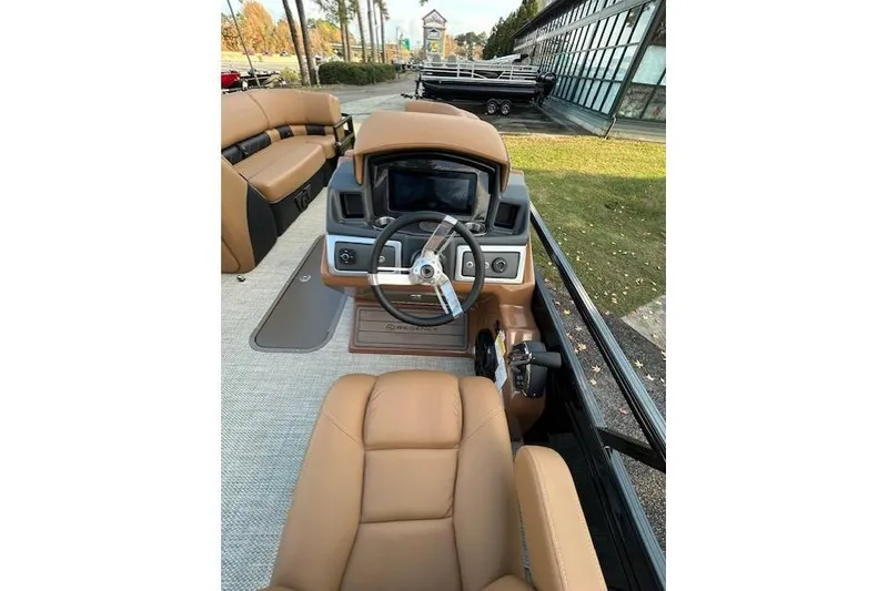 Slide: The Image of 2025 Regency 230 LE3 Sport boat interior with tan seating and modern dashboard. - 8