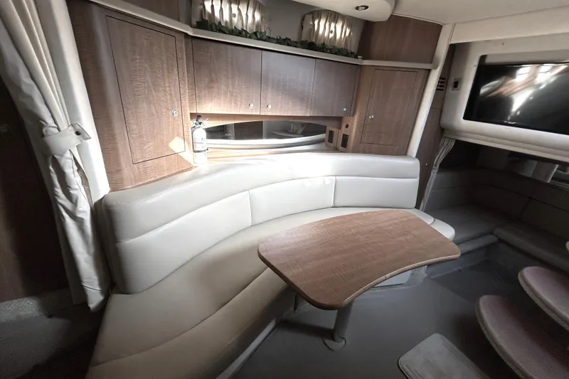 Slide: The Image of Interior of 2006 Sea Ray 320 Sundancer with curved seating and wooden table. - 26