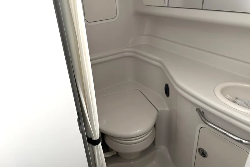 Slide: The Image of 2006 Sea Ray 320 Sundancer bathroom with toilet and sink, featuring sleek white design. - 36