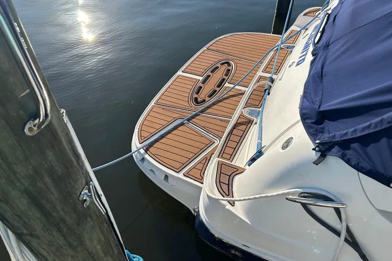Slide: The Image of 2006 Sea Ray 320 Sundancer docked, featuring a wooden swim platform and blue cover. - 8