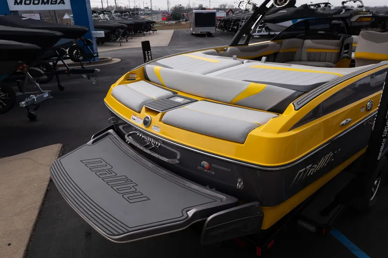 Slide: The Image of 2014 Malibu Wakesetter 24 MXZ boat with yellow and gray design, displayed outdoors. - 8