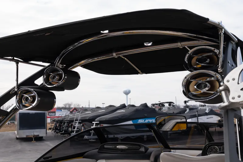Slide: The Image of 2014 Malibu Wakesetter 24 MXZ with premium speakers and sleek design in a showroom. - 9