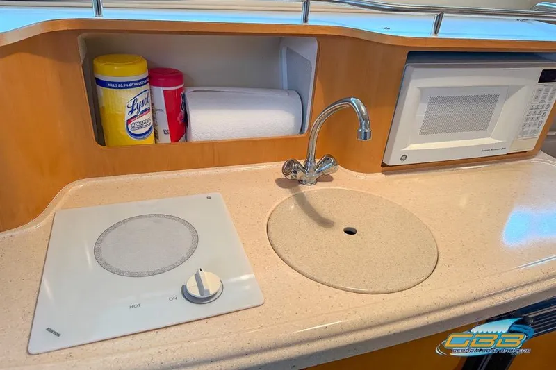 Slide: The Image of 2001 Chris-Craft 26 Constellation yacht kitchenette with sink, stove, and microwave. - 14