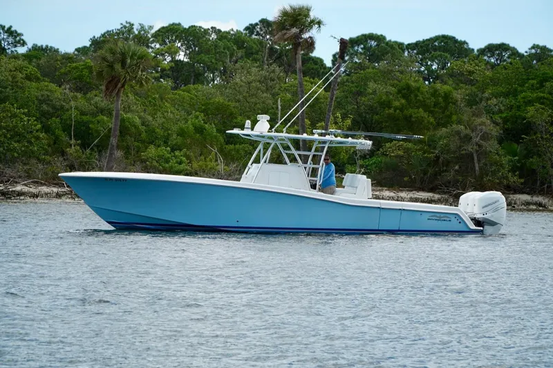 Slide: The Image of Invincible boat on calm water near lush green shoreline, featuring sleek design and powerful engines. - 2