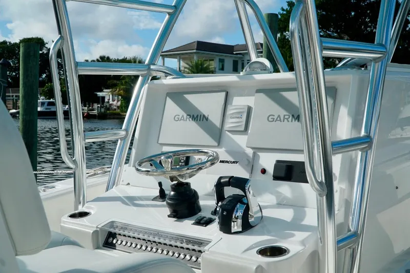 Slide: The Image of Invincible boat console with Garmin displays and Mercury controls, docked by waterfront homes. - 22
