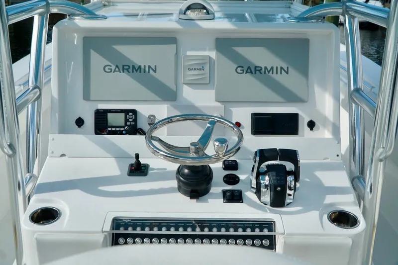 Slide: The Image of Boat helm with Garmin displays and controls, Invincible make, featuring steering wheel and throttle. - 23