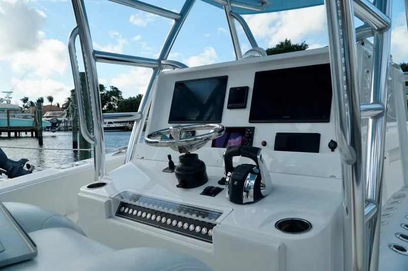 Slide: The Image of Invincible boat dashboard with steering wheel, controls, and screens, docked by the water. - 26