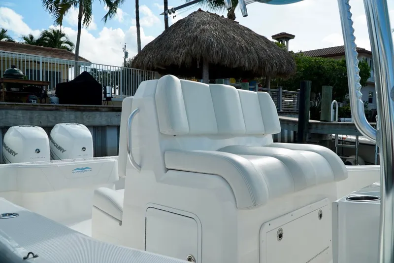 Slide: The Image of Invincible boat with white seating and Mercury engines docked near a tropical setting. - 27