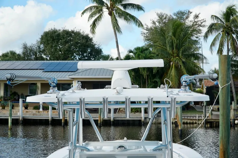 Slide: The Image of Invincible boat with radar, docked near a house with solar panels and palm trees. - 32