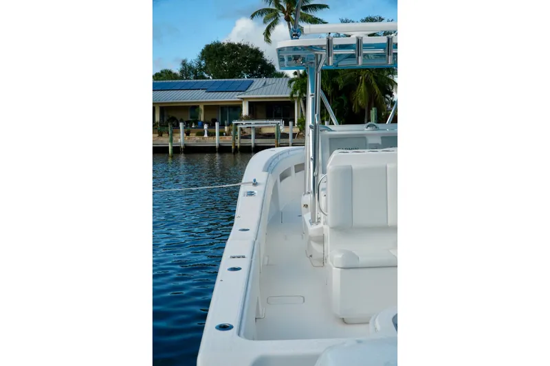 Slide: The Image of Invincible boat docked by waterfront house with palm trees and clear blue sky. - 42