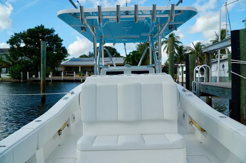 Slide: The Image of Invincible boat with white seating and blue canopy docked by waterfront homes. - 46