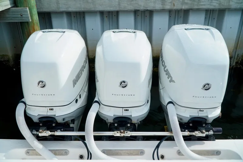Slide: The Image of Triple Mercury FourStroke outboard engines on an Invincible boat, docked by a wooden pier. - 56