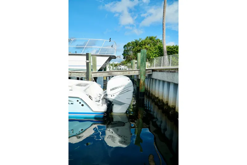 Slide: The Image of Invincible boat with Mercury engine docked by a wooden pier under a clear blue sky. - 58