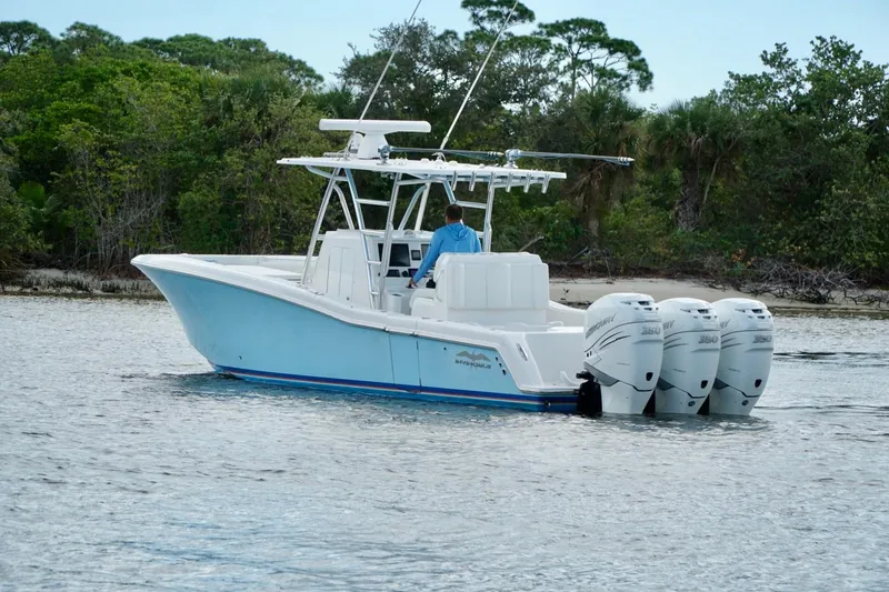 Slide: The Image of Invincible boat with triple outboard engines cruising near lush shoreline. - 6