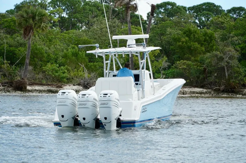 Slide: The Image of Invincible boat with triple 350 engines cruising near lush green shoreline. - 8