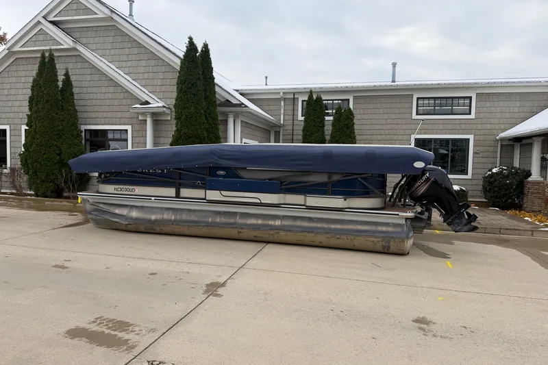 Slide: The Image of 2017 Crest 230SL Classic pontoon boat covered and parked near a house. - 17