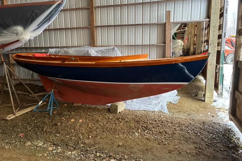 The Image of 1981 Herreshoff Doughdish 12.5 footer sailboat in storage, featuring classic wooden design. - 0