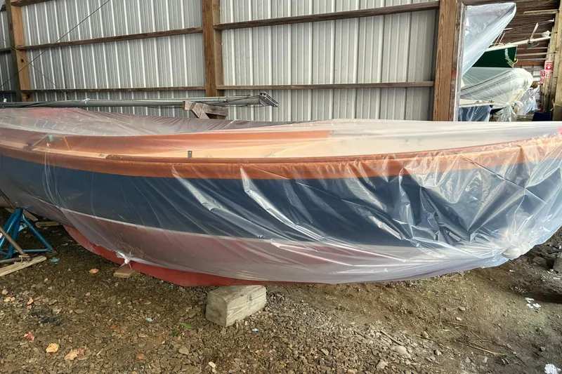 Slide: The Image of 1981 Herreshoff Doughdish 12.5 footer sailboat covered in plastic, stored indoors. - 1