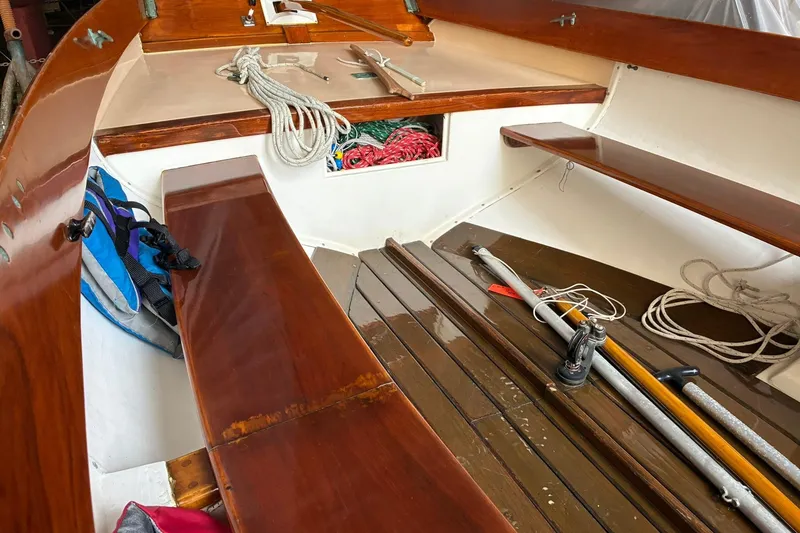 Slide: The Image of 1981 Herreshoff Doughdish 12.5 footer interior with wooden benches and sailing equipment. - 14