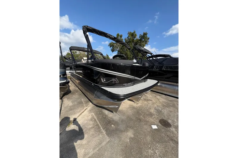 The Image of 2026 Avalon LSZ ELITE pontoon boat with sleek black design, docked under blue sky. - 1
