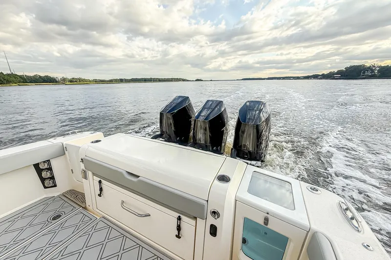 Slide: The Image of 2024 Scout 377 LXF boat with triple outboard engines cruising on a calm lake. - 72
