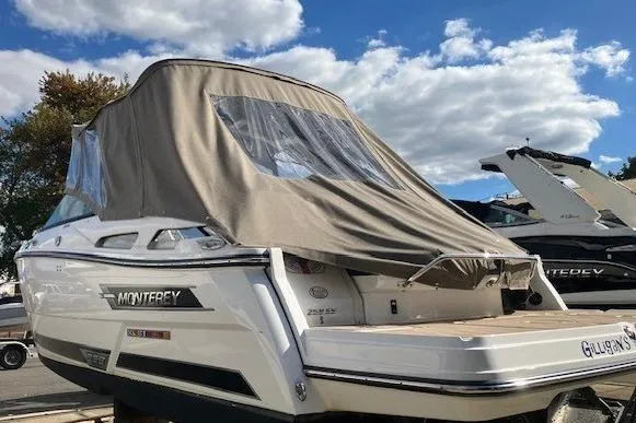 Slide: The Image of 2024 Monterey 258SS Super Sport boat with cover, docked under a blue sky. - 2