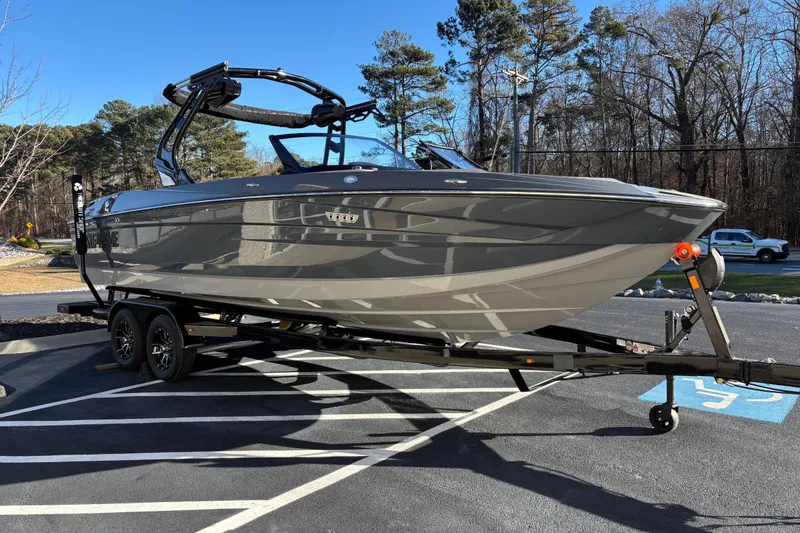 Slide: The Image of 2026 Supreme S240 boat on trailer in parking lot, surrounded by trees. - 2