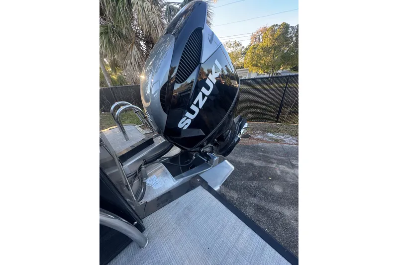 Slide: The Image of 2026 Tahoe Pontoon CASCADE QUAD LOUNGER with Suzuki outboard motor, parked outdoors. - 6