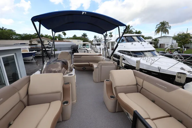 Slide: The Image of 2019 Veranda 22 VR pontoon boat with spacious seating and canopy, docked near luxury yachts. - 13