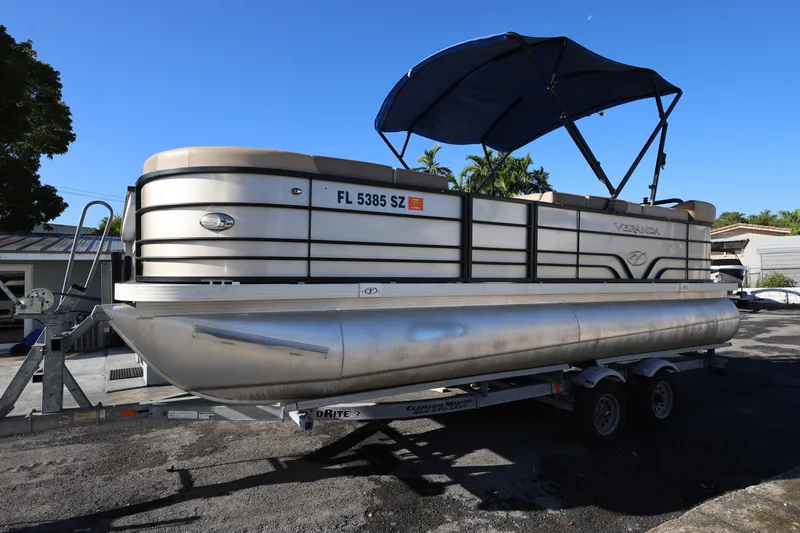 Slide: The Image of 2019 Veranda 22 VR pontoon boat on trailer with blue canopy, parked outdoors. - 7