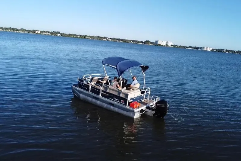 Slide: The Image of 2021 Sun Tracker Bass Buggy 16 XL pontoon boat cruising on a calm lake. - 17
