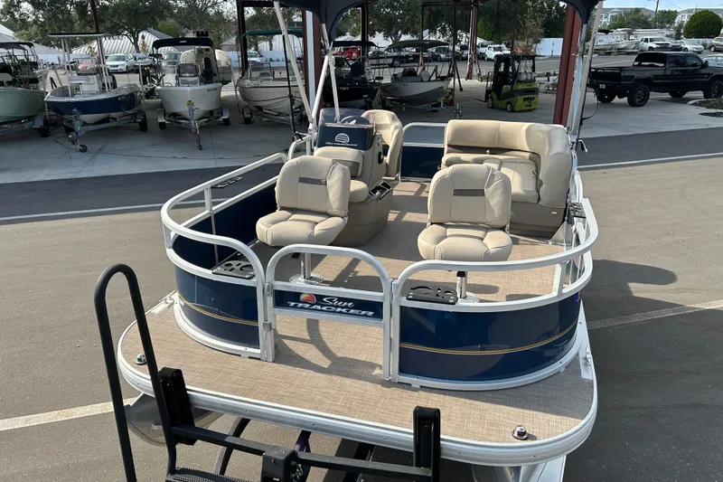 Slide: The Image of 2021 Sun Tracker Bass Buggy 16 XL pontoon boat with beige seating, displayed outdoors. - 6