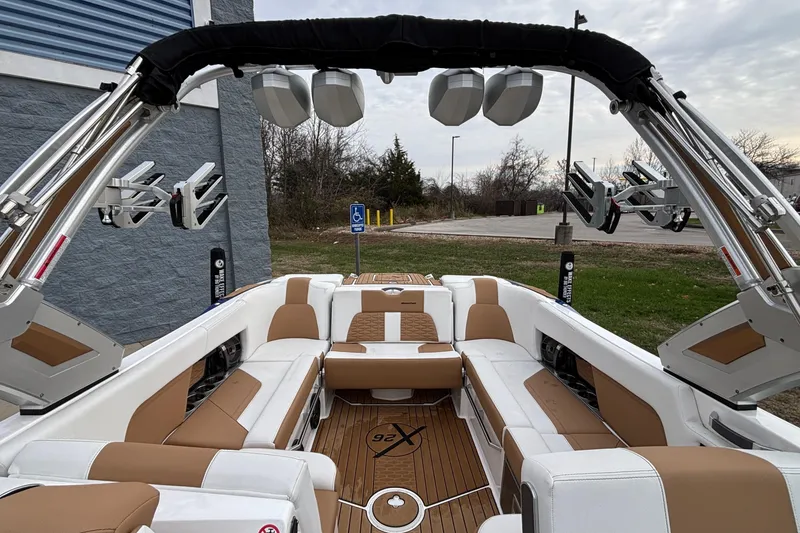 Slide: The Image of 2022 MasterCraft X26 boat interior with tan and white seating, outdoor setting. - 10