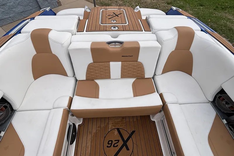 Slide: The Image of 2022 MasterCraft X26 boat interior with tan and white seating, teak flooring. - 11