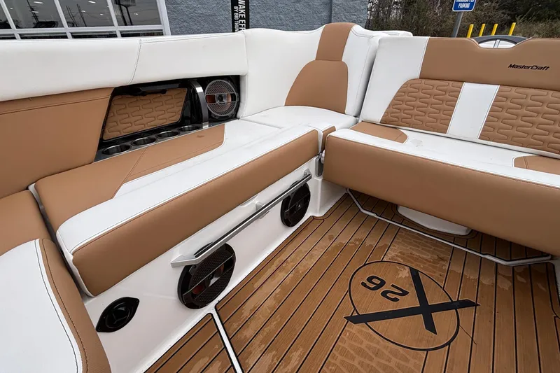 Slide: The Image of 2022 MasterCraft X26 boat interior with tan and white seating, cup holders, and speakers. - 13