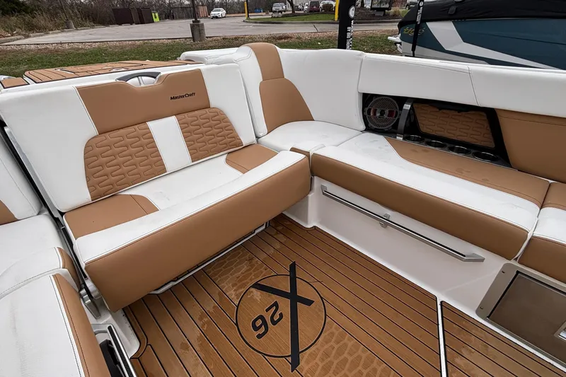 Slide: The Image of 2022 MasterCraft X26 boat interior with tan and white seating, teak flooring. - 15