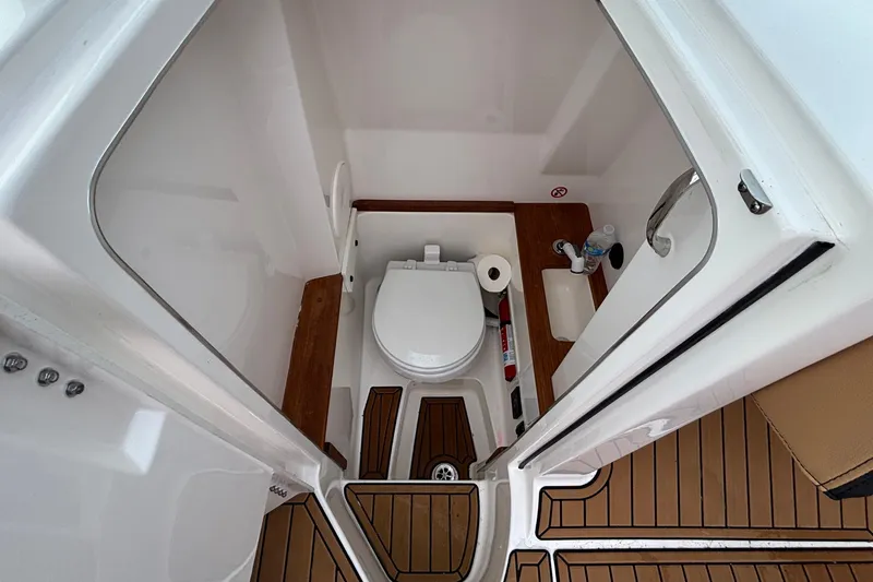 Slide: The Image of 2022 MasterCraft X26 boat bathroom with toilet, sink, and wooden flooring. - 23