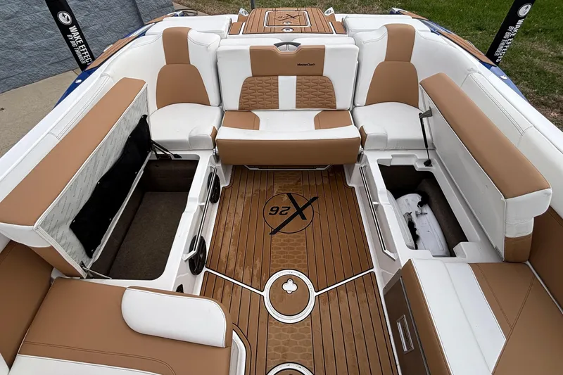 Slide: The Image of 2022 MasterCraft X26 boat interior with tan and white seating, open storage compartments. - 30