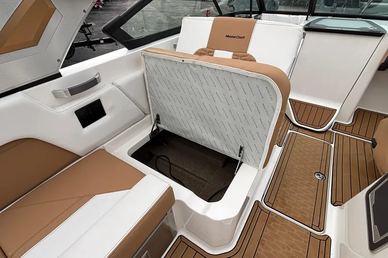 Slide: The Image of 2022 MasterCraft X26 boat interior with open storage compartment and tan seating. - 33