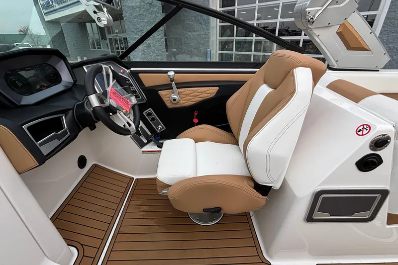 Slide: The Image of 2022 MasterCraft X26 boat interior with tan and white seating, modern dashboard, and wood flooring. - 37