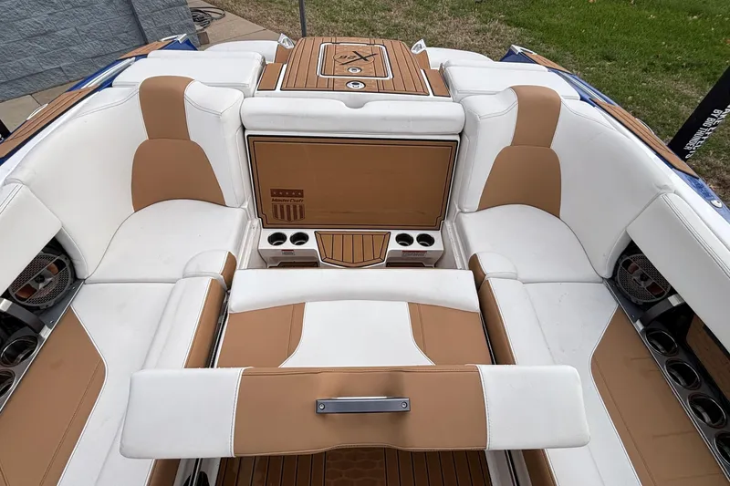 Slide: The Image of 2022 MasterCraft X26 boat interior with white and tan seating, cup holders, and speakers. - 41