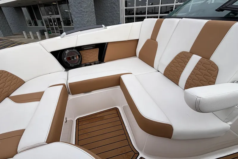 Slide: The Image of 2022 MasterCraft X26 boat interior with white and tan seating, featuring a speaker and wood flooring. - 54