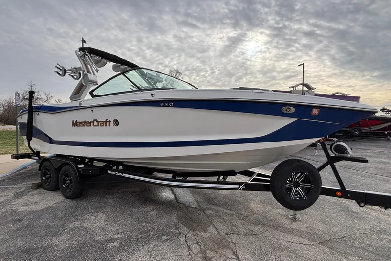 Slide: The Image of 2022 MasterCraft X26 boat on trailer under cloudy sky. - 58