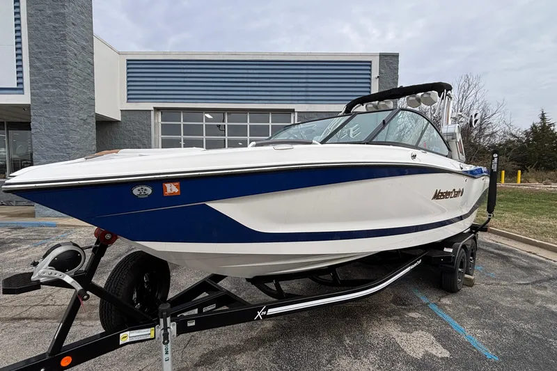 Slide: The Image of 2022 MasterCraft X26 boat on trailer, parked outside a building. - 59