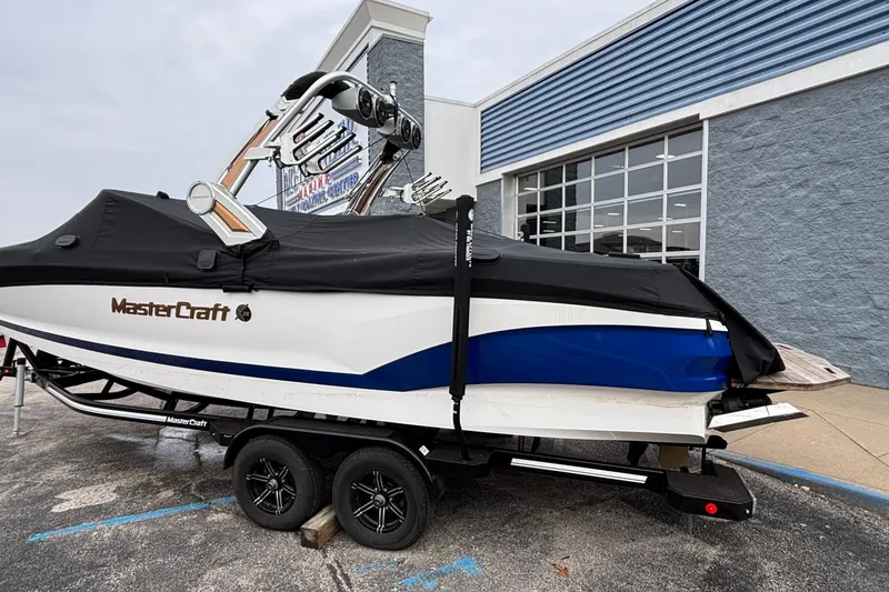 Slide: The Image of 2022 MasterCraft X26 boat with cover on trailer, parked outside a building. - 6