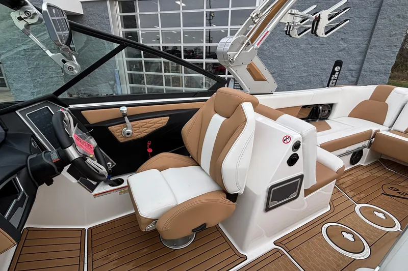 Slide: The Image of 2022 MasterCraft X26 boat interior with tan and white seating, modern dashboard, and wood flooring. - 8